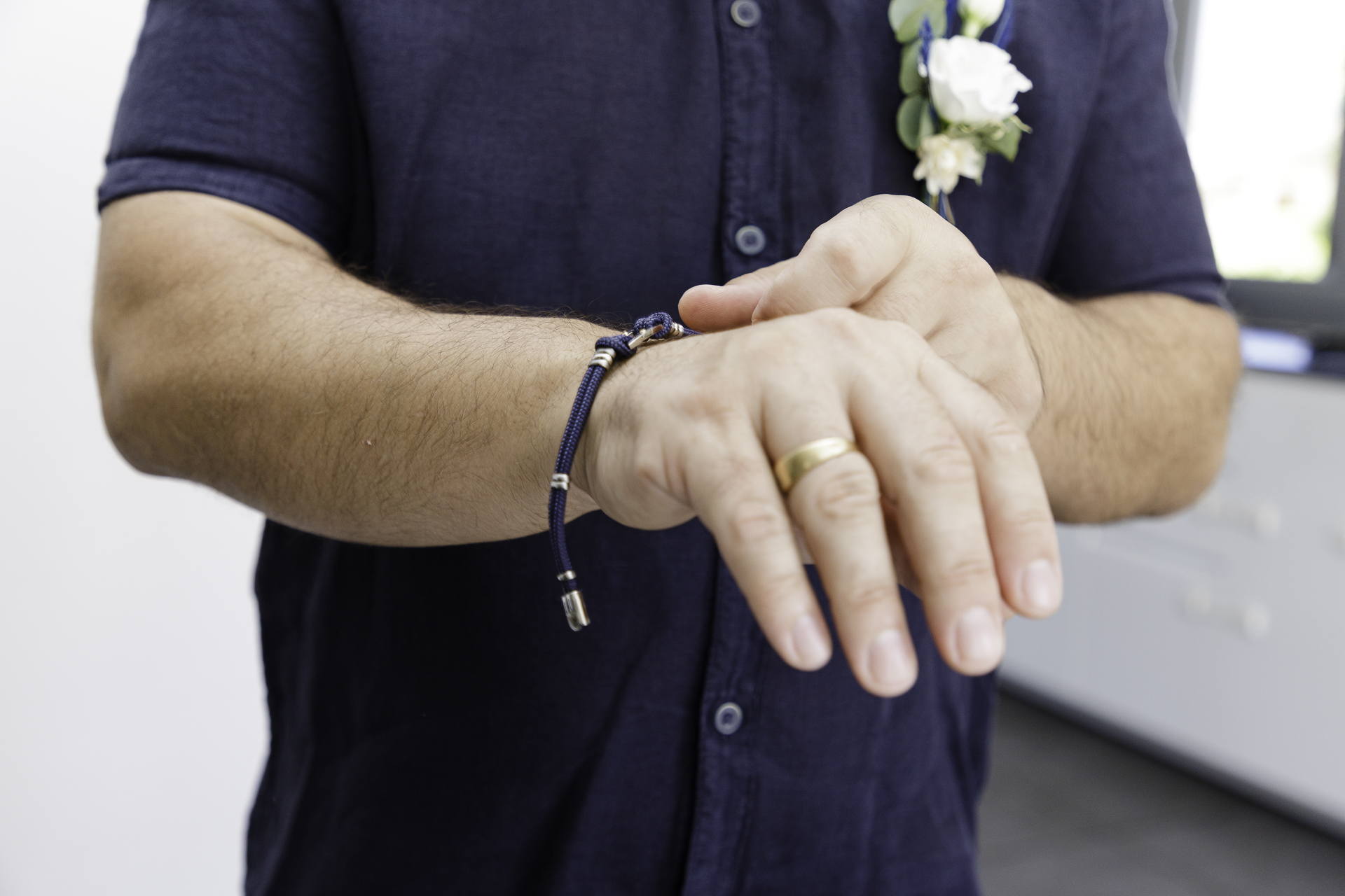 Le marié se prépare à sa journée. Il enfile un bracelet pour compléter sa tenue.